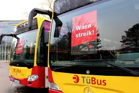 Warnstreik!" sowie das Logo der Gewerkschaft ver.di. Im Hintergrund sind Bäume und ein Gebäude zu sehen.