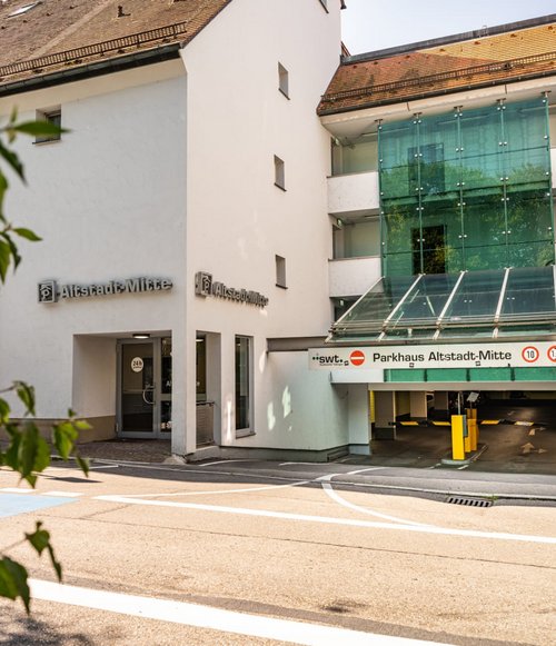 Alt-Text: Einfahrt zum Parkhaus Altstadt-Mitte mit Glasfassade und Beschilderung, links daneben der Zugang für Fußgänger.